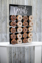 Load image into Gallery viewer, Black Acrylic Donut Wall, with Gold or Silver Donut Text. 43cm x 65cm. Holds 20-40 Donuts. Freestanding